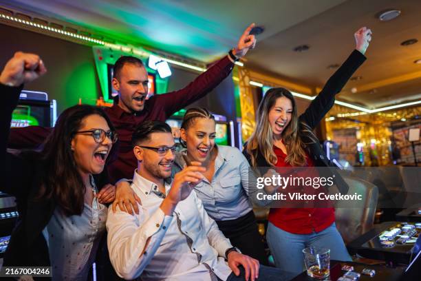 group of friends playing games on a slot machine in a casino - casino interior photos et images de collection