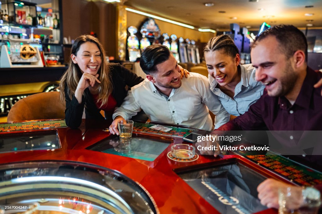 Happy group of friends playing roulette in casino