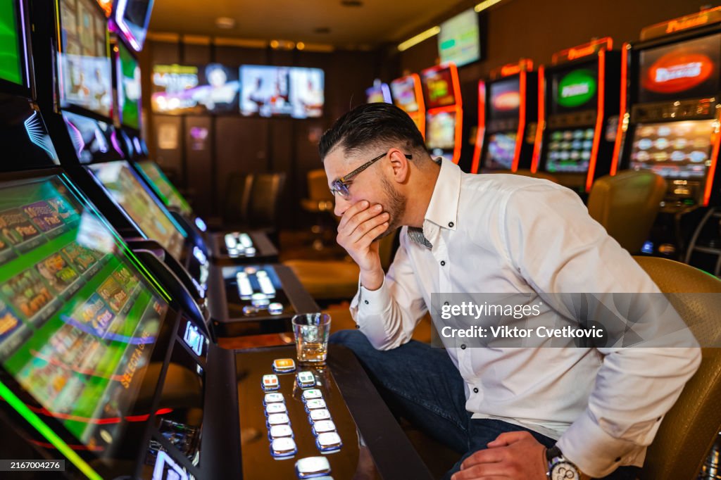 Men loosing his money on slot machine in the casino
