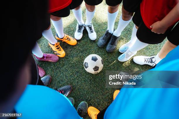 team huddle around soccer ball on field - soccer shoe stock pictures, royalty-free photos & images