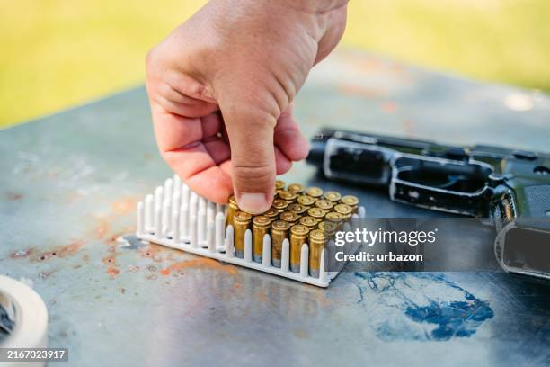 mid-adult man taking bullets out of the case to reload his handgun for shooting practice - reload gun stock pictures, royalty-free photos & images
