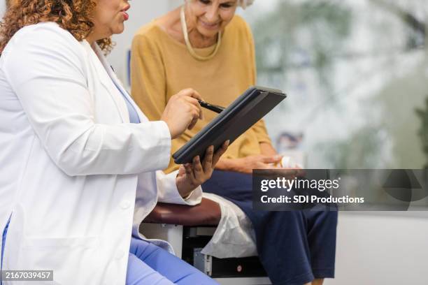 il medico donna irriconoscibile legge le informazioni sul tablet digitale con il suo paziente - cartella clinica elettronica foto e immagini stock