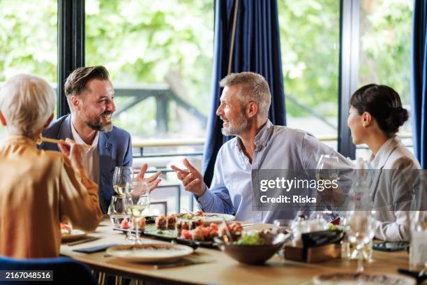 gruppo di amici che si godono un pasto in un ristorante - cena con invitati foto e immagini stock