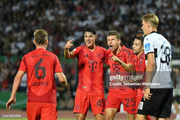 Thomas Mueller of FC Bayern Muenchen celebrates with team mates Aleksandar Pavlovic and Raphael Guerreiro after scoring his team's first goal during...