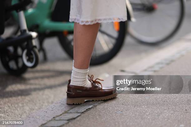 Fashion Week guest is seen wearing a calf-length white skirt with lacy detail, white socks, and brown leather boat shoes from Timberland before the...