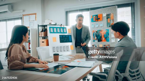 team che analizza i progetti dell'interfaccia delle app mobili in office - studio di design foto e immagini stock