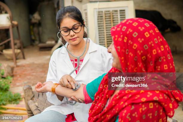 doctora india examinando a una paciente mayor rural con estetoscopio durante una visita domiciliaria en el pueblo. - países en vías de desarrollo fotografías e imágenes de stock