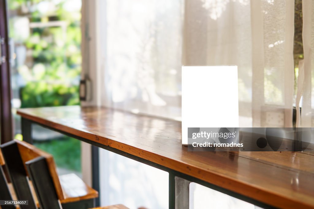 Empty Frame Display on Wooden Table in Cozy Cafe, Working space, Sale Discount banner. Blank poster for advertising and business promotion.