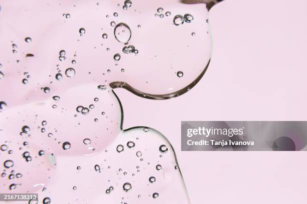 texture of transparent gel or serum cosmetic with bubbles on pink background. liquid hyaluronic acid gel. - aminoácido fotografías e imágenes de stock