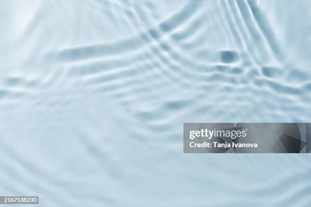 light blue transparent clear water surface texture with ripples, waves in sunlight and light reflections - water photos et images de collection
