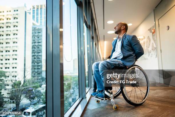 mature wheelchair businessman looking away contemplating at office - quadriplegic stock pictures, royalty-free photos & images