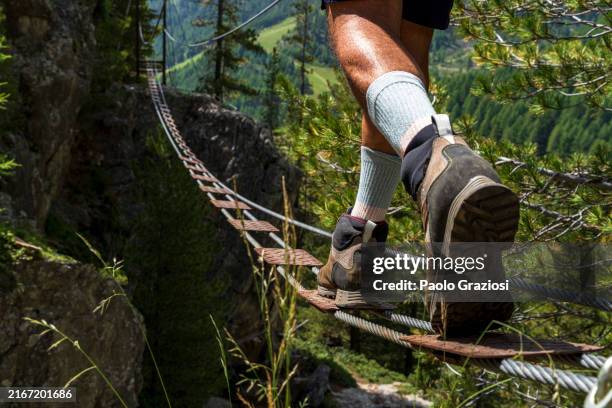 persönliche perspektive eines wanderers, der auf einer hängebrücke auf einem klettersteig läuft - höhenangst stock-fotos und bilder