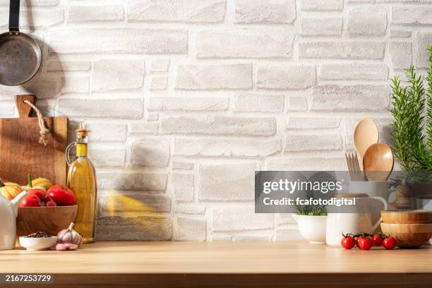 kitchen countertop with utensils, vegetables and spices on brick wall background. copy space available - pan keukengereedschap stockfoto's en -beelden