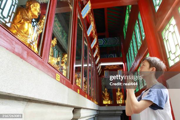 boy worships buddha, in the temple - boeddhisme stockfoto's en -beelden