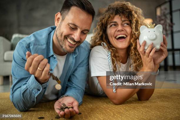 happy young couple saving money for their next investment, shopping or vacation - savings stock pictures, royalty-free photos & images