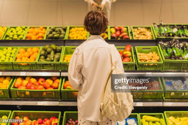 woman in vegetable department of supermarket. - magasin de fruits et légumes photos et images de collection
