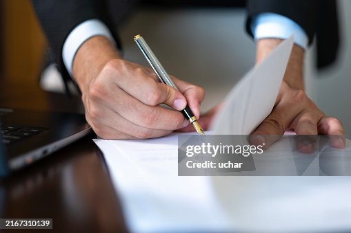 Close-up of hands of unknown businessman in suit signing official document Close-up of hands of unknown businessman in suit signing official document