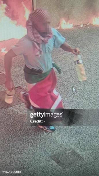 This CCTV image obtained by AFP on August 24, 2024 shows a potential suspect carrying two empty bottles and a Palestinian flag draped around his...