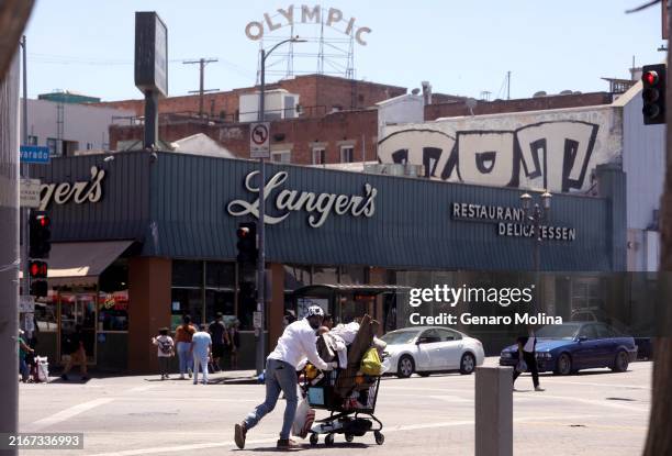 Man walks with his belongings in a shopping cart across the street from Langer's Deli, also known as Langer's Delicatessen-Restaurant, in in the...