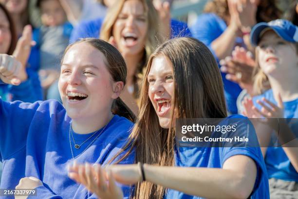 teenage girls cheer on football team from crowded stadium stand seats - american football sport stock pictures, royalty-free photos & images