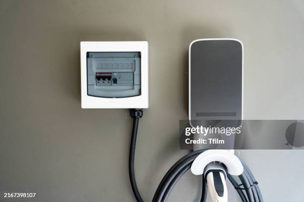 wall-mounted electric vehicle charging station with cable - battery charger stock pictures, royalty-free photos & images