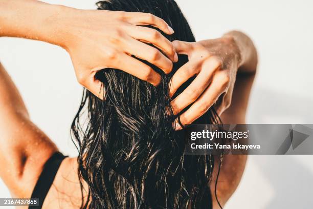 a beautiful unrecognizable woman washing hair in an outdoor shower - shampoo stockfoto's en -beelden
