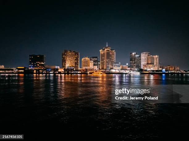 new orleans, louisiana riverfront and central business district skyline from the mississippi river at night - bridge architecture up close night stock pictures, royalty-free photos & images