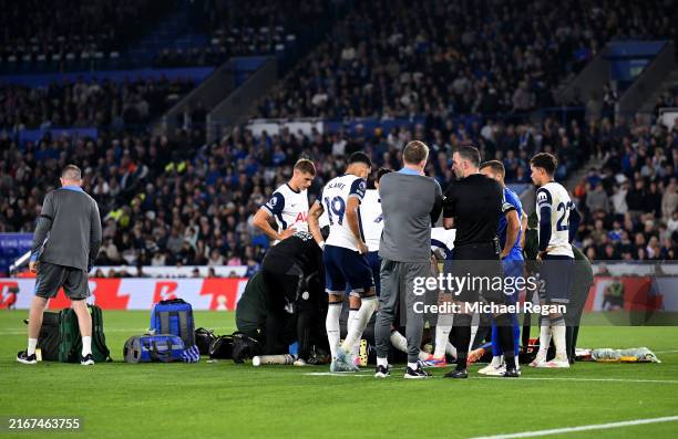 Rodrigo Bentancur of Tottenham Hotspur receives medical attention after a clash of heads with Abdul Fatawu of Leicester City during the Premier...
