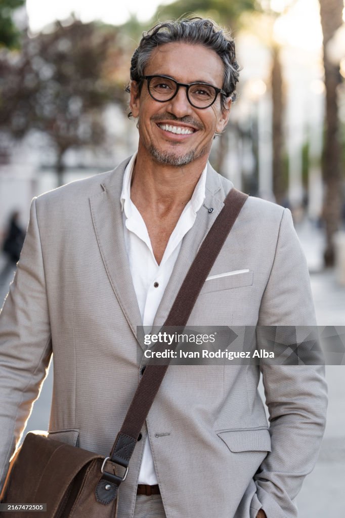 Cool handsome mature businessman smiling at camera in the street