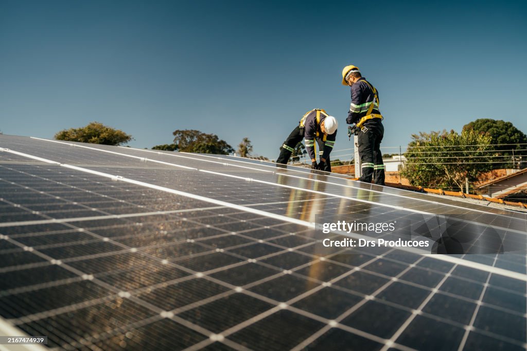 Two workers installing solar panel on roof