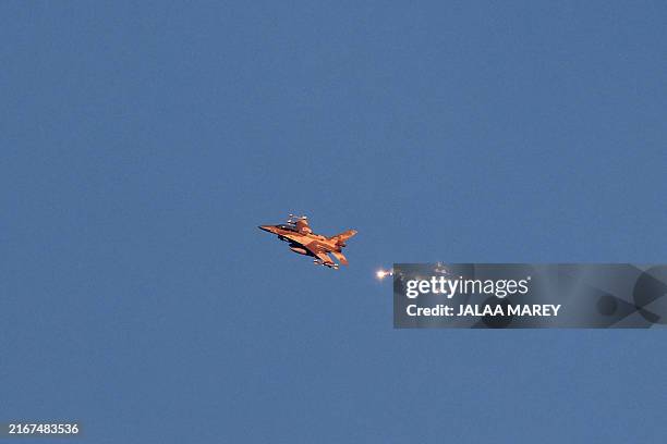 This photo taken from a position in northern Israel shows an Israeli Air Force fighter jet firing flares as it flies to intercept a hostile aircraft...