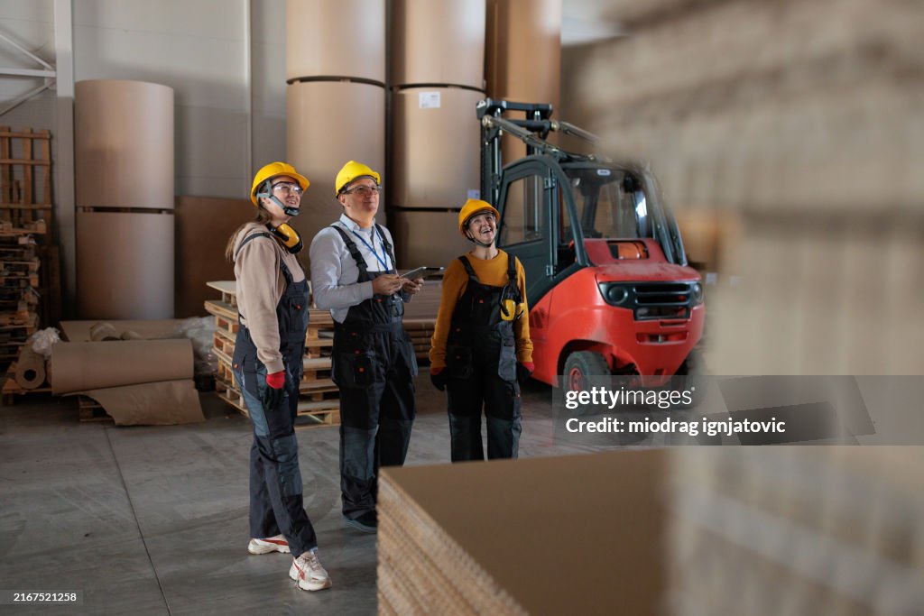 Paper factory workers inspecting products in a warehouse