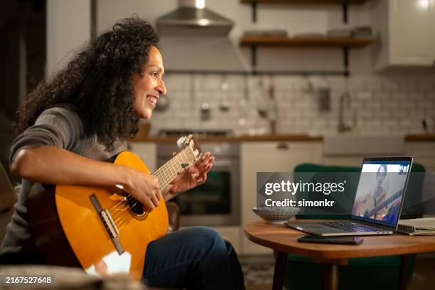 mature woman playing guitar in front of laptop - guitar stock pictures, royalty-free photos & images