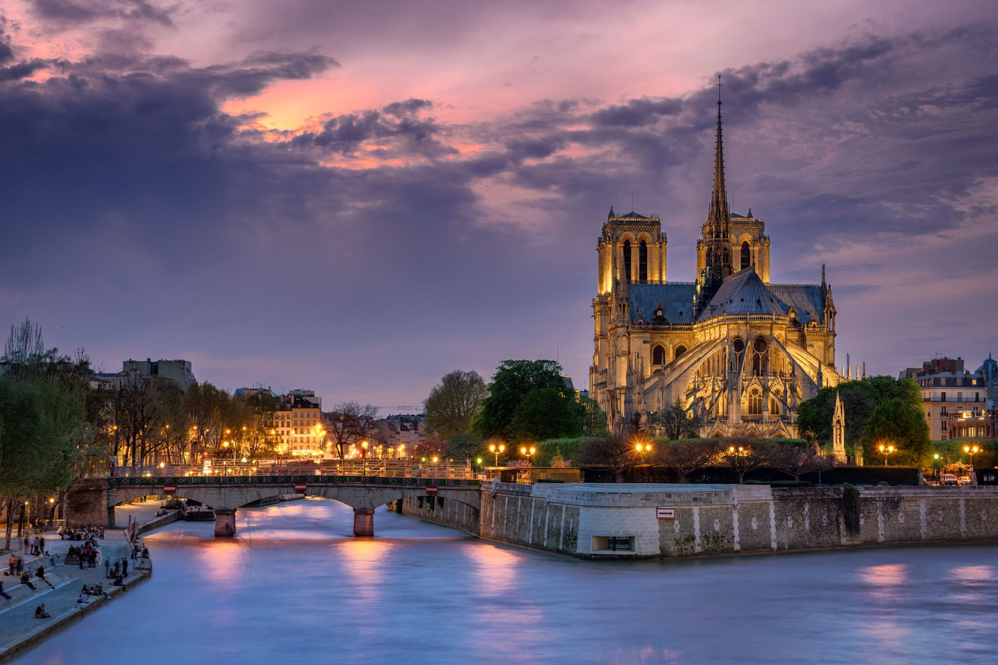 Notre Dame De Paris By Seine River Against Cloudy Sky During Sunset Notre Dame De Paris By Seine River Against Cloudy Sky During Sunset