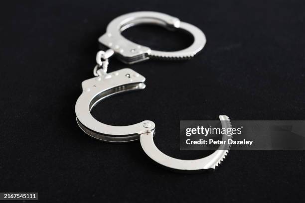 handcuffs on black background - bestrafung stock-fotos und bilder