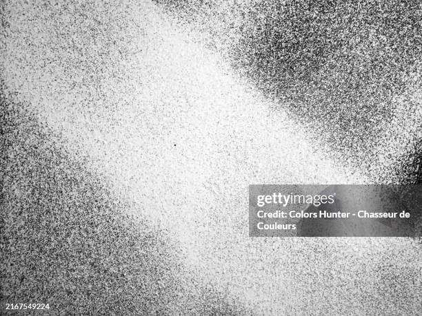 white and grey spray paint on a black wall. rough texture. natural light. black and white. photograph taken on a construction site in paris, france. - spray paint stock pictures, royalty-free photos & images
