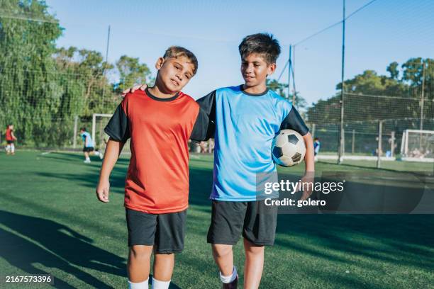 two boys from opponent teams walking embraced after match - sports training camp stock pictures, royalty-free photos & images