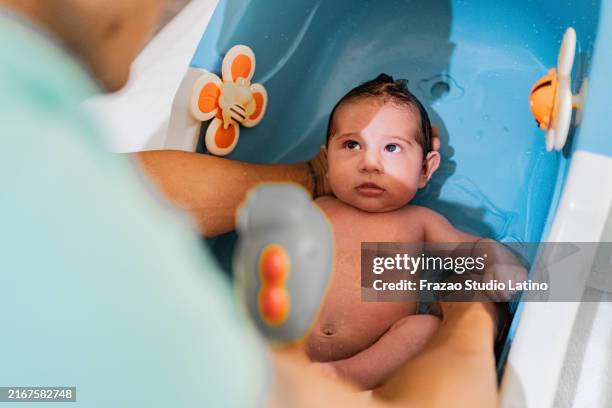 father bathing baby son in bathtub at home - taking a bath stock pictures, royalty-free photos & images