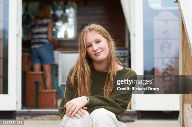 a teenage girl sitting on a deck outside an eco lodge - hand on knee stock pictures, royalty-free photos & images