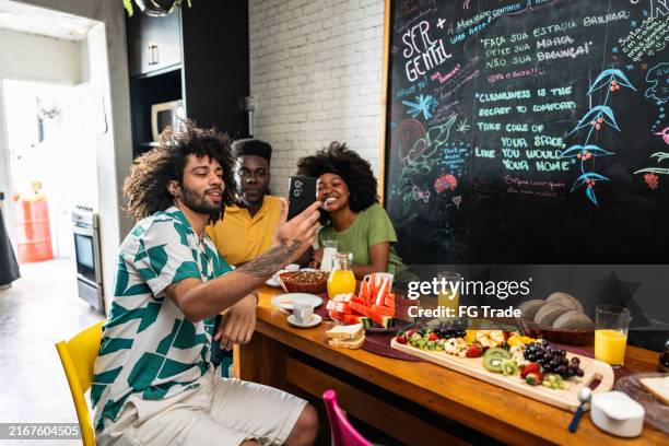 friends using mobile phone during breakfast at a hostel - holiday zoom stock pictures, royalty-free photos & images