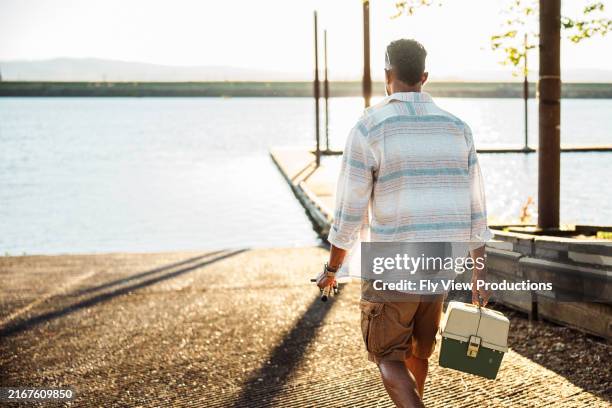 hombre dirigiéndose al río para pescar en una tarde soleada - la tarde fotografías e imágenes de stock