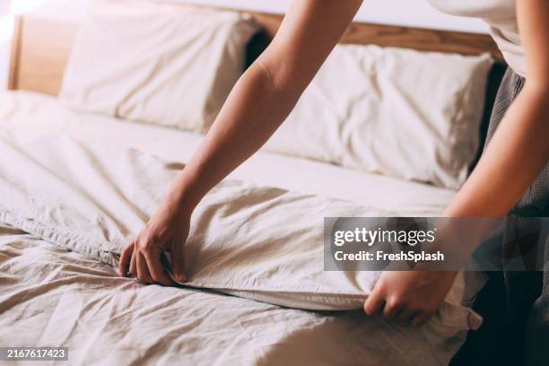 persona che fa il letto con lenzuola bianche fresche a casa - lenzuolo foto e immagini stock