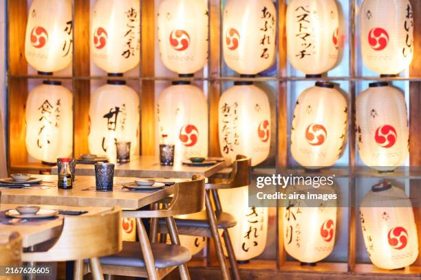 side view of empty tables in a chinese restaurant with a group of lamps on the background wall - empty plate side view stock pictures, royalty-free photos & images