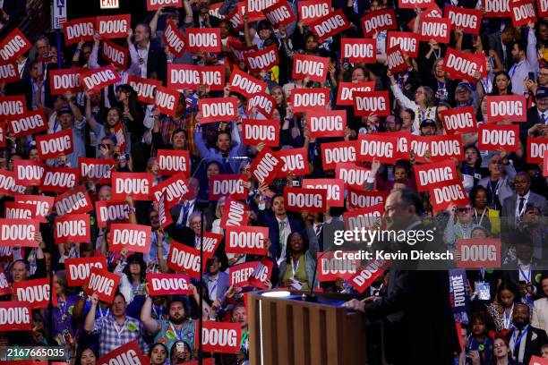 Attendees hold "Doug" signs as second gentleman Doug Emhoff speaks on stage during the second day of the Democratic National Convention at the United...