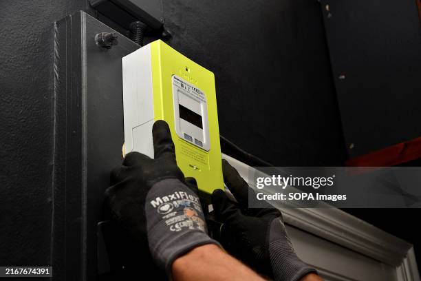 Technician from the Enedis company wearing safety gloves replaces the cover of a Linky electricity meter.