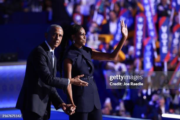 Former U.S. President Barack Obama gestures to former first lady Michelle Obama as he arrives to speak on stage during the second day of the...