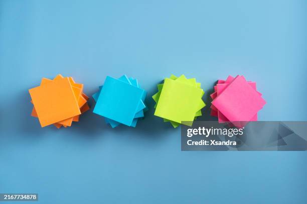 bunte haftnotizen, ordentlich gestapelt auf blauem hintergrund - miteinander verbunden stock-fotos und bilder