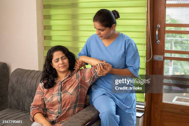 female doctor examining female patient's hand at home - sports medicine stock pictures, royalty-free photos & images