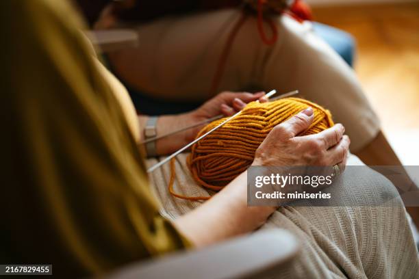 elderly woman knitting with caregiver assistance at home - knitting stock pictures, royalty-free photos & images