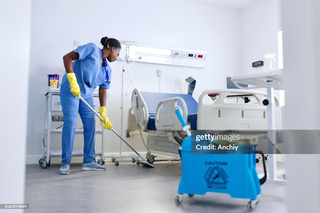 A dedicated staff member cleans the floor of a hospital room